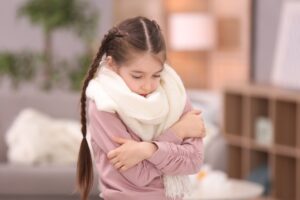 little girl shivering and wearing a scarf indoors
