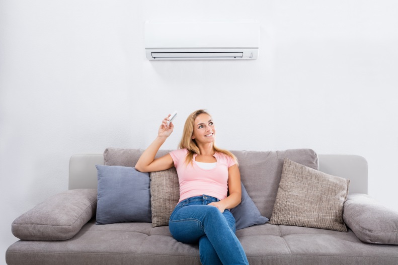 woman sitting on a couch under her air conditioner